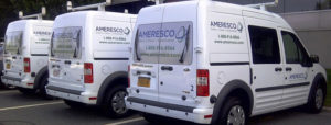 Daytime view of three Ameresco-branded minivans parked outside a facility