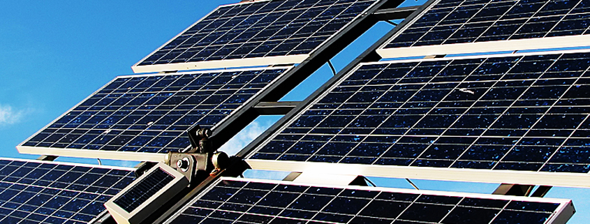 Daytime closeup of solar panels mounted on a rack against a blue sky