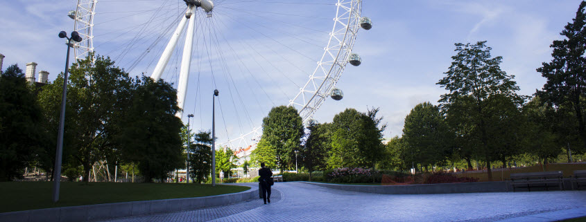 Daytime exterior of a London riverbank park with the London Eye in the background