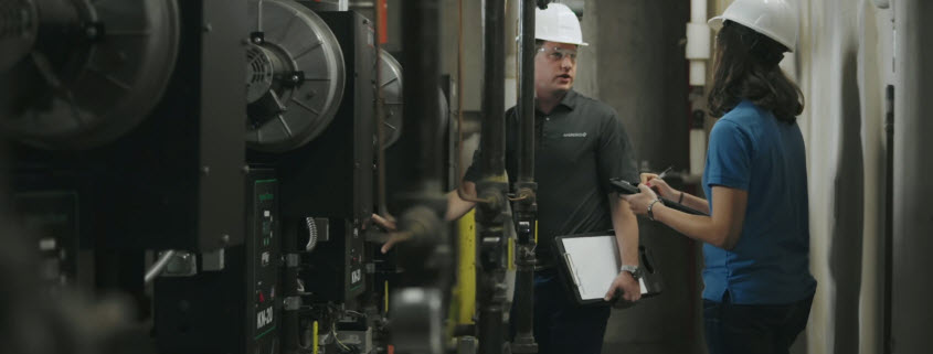 Two engineers examine equipment in a central heating and cooling plant